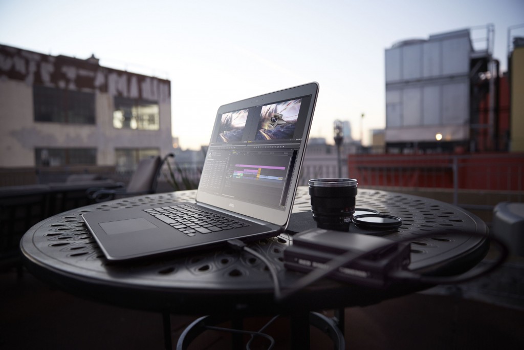 Dell Precision M3800 mobile workstation placed on an outdoor table  connected to a camera and next to a camera lens.