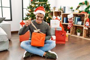 Šťastný muž otvára vianočné darčeky bez obáv, pretože svoje želania poslal cez PLANEO Vianočný zoznam