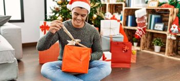 Šťastný muž otvára vianočné darčeky bez obáv, pretože svoje želania poslal cez PLANEO Vianočný zoznam