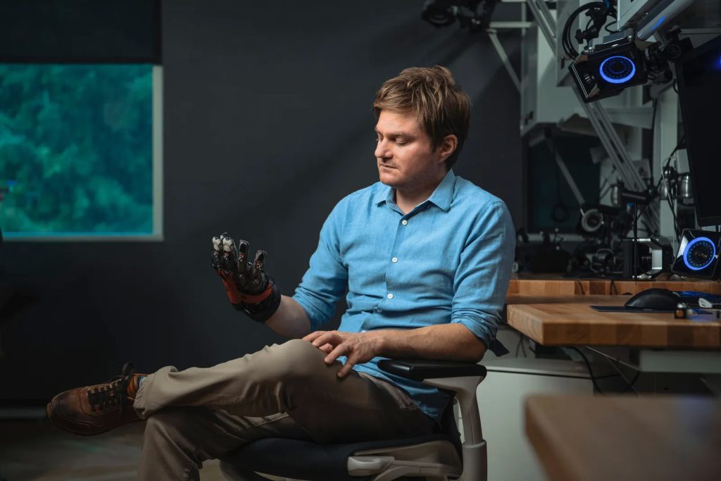 Sean Keller, vedúci výskumného centra Reality Labs spoločnosti Facebook/Meta, s nasadenou haptickou rukavicou