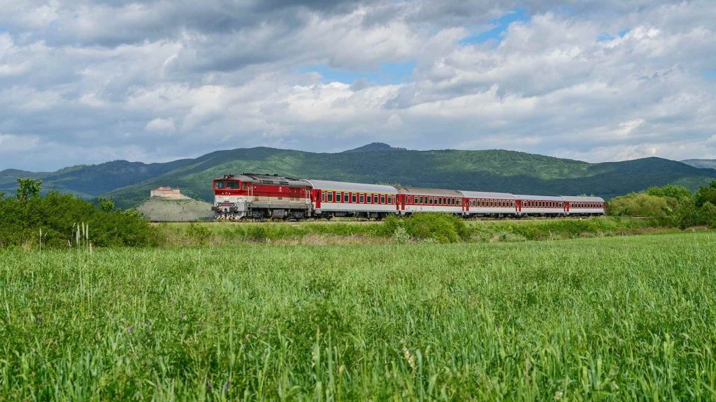 Panoráma malebnej prírody spolu s vlakom ZSSK, v pozadí vidieť hrad Krásna hôrka