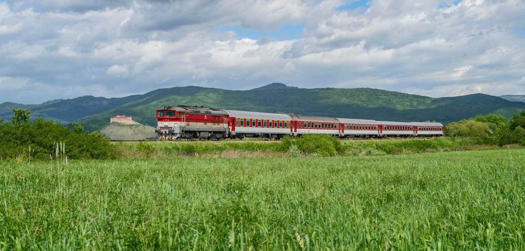 Panoráma malebnej prírody spolu s vlakom ZSSK, v pozadí vidieť hrad Krásna hôrka