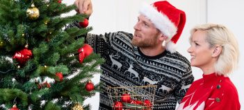Žena s mužom vešajú ozdoby na vianočný stromček