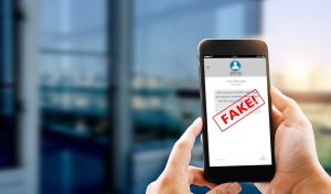 Mobilných telefón v rukách s nápisom FAKE na displeji