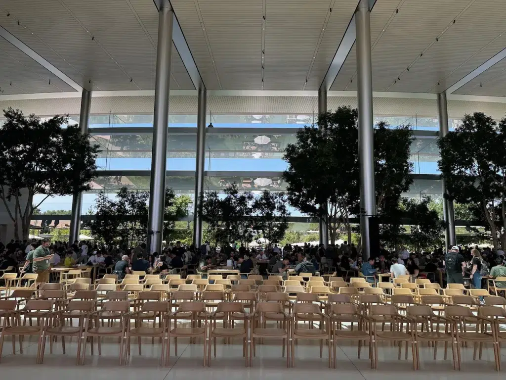 Caffè Macs počas voľného programu medzi keynotes. Presklená hala s vysokými stĺpmi a stromami sa medzi prezentáciami menila na oddychový priestor